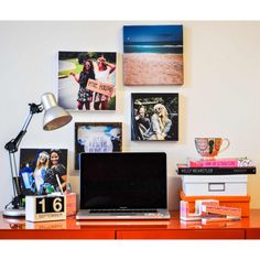 a laptop computer sitting on top of a wooden desk next to pictures and a lamp