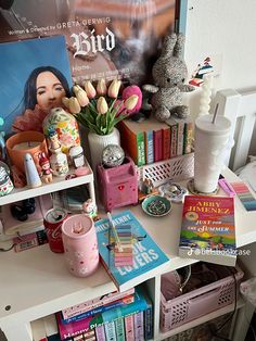 a white desk topped with lots of books and vases