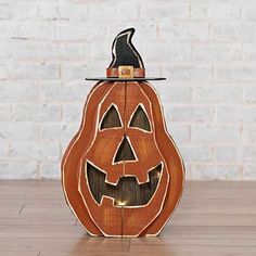 a wooden carved pumpkin with a black hat on top