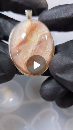 a close up of a person's hand holding a ring with a stone in it