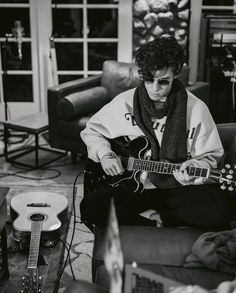 a man sitting on a couch playing an electric guitar