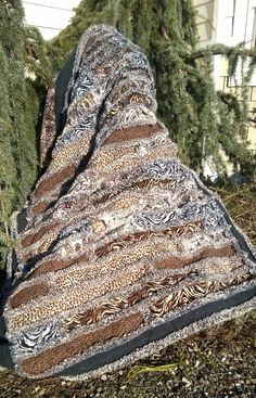 an animal print blanket sitting on top of a pile of dirt next to a tree