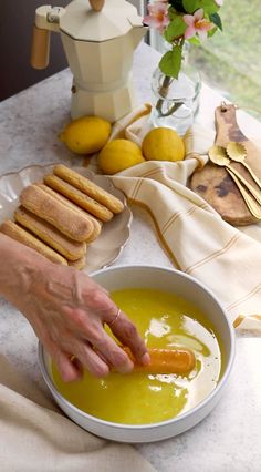 a person is dipping some bread into a bowl of soup with lemons in the background