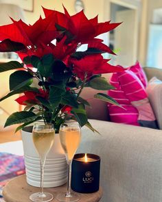 two wine glasses are sitting on a table with a candle and poinsettia