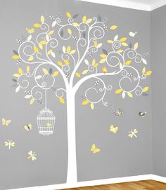 a white tree with yellow and gray butterflies on it, next to a grey wall