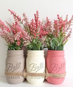 three painted mason jars with flowers in them