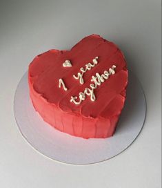 a red heart shaped cake with writing on the top and bottom that says, year together