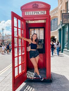 a woman posing in a red phone booth