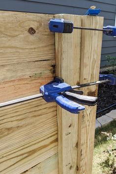 a pair of pliers are attached to the side of a wooden fence with blue handles