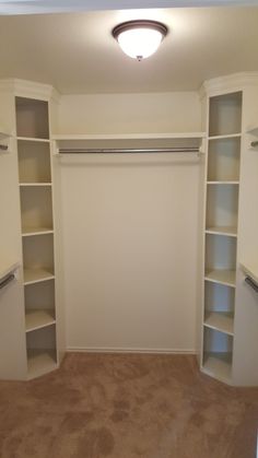 an empty walk in closet with white shelves