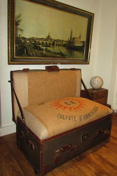 an old suitcase is sitting on the floor in front of a wall with a painting above it