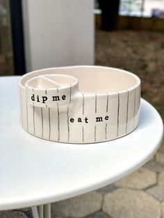 a white bowl sitting on top of a table next to a cup with writing on it