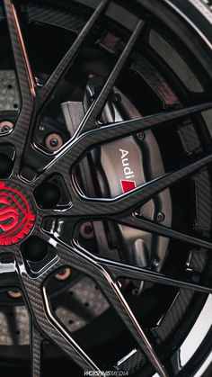 the front wheel of a sports car with red emblems on it's rim