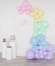 the balloon arch is decorated with pastel colors