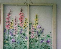 an old window with flowers painted on the glass and hanging from it's side