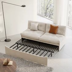 a white couch sitting on top of a wooden floor next to a table and lamp