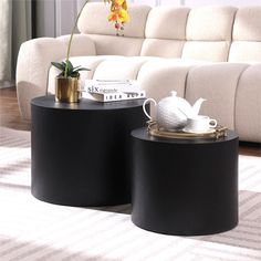 two black tables sitting on top of a carpeted floor next to a white couch