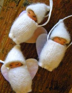 three little white knitted mice with faces on them sitting on a wooden floor next to string