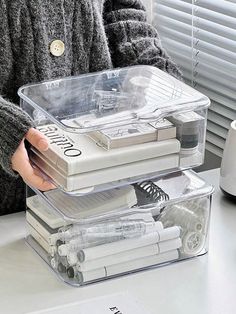 a person holding a plastic container filled with different types of items on top of a table