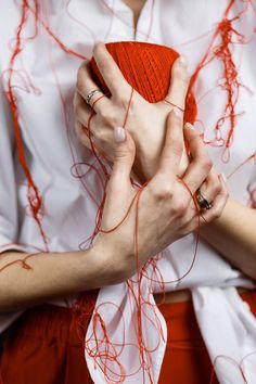 a woman is holding an orange ball of yarn in her hands while wearing red shorts