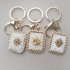 four keychains with beaded designs on them are sitting next to each other