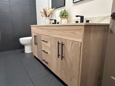 a bathroom with a sink, toilet and wooden cabinetry in it's center