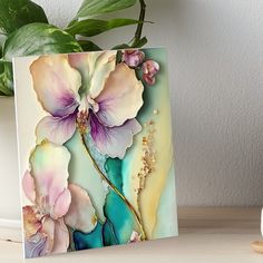 a painting of flowers on a table next to a potted plant with green leaves