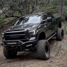 a black truck driving down a dirt road