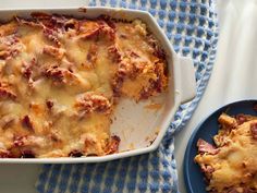 a casserole dish on a blue and white cloth next to a bowl of food