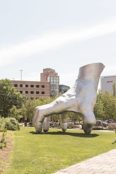 a large foot statue sitting on top of a lush green field