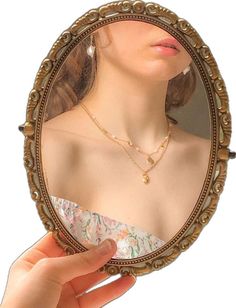 a woman's hand holding up a mirror to her face