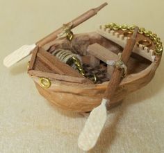 a small wooden boat filled with lots of stuff on top of a table next to a pair of scissors