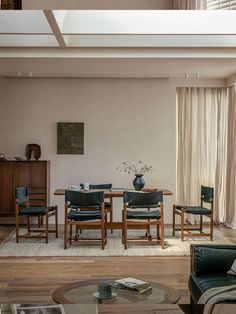 a living room filled with furniture and a wooden table in front of a large window