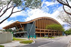 a large building sitting on the side of a road next to tall grass and trees