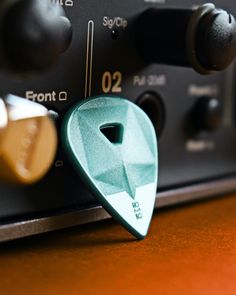 a green guitar picker sitting on top of a black and silver amperator