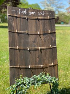 a wooden sign that says find your seat on the grass in front of some bushes