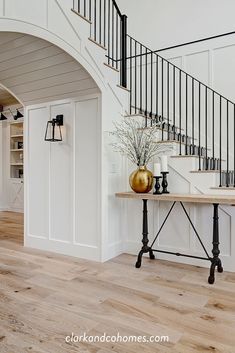 an entryway with a table, vase and stairs