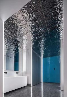 an empty bathroom with mirrors and sinks in the center, all covered by water droplets