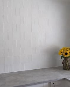 a vase filled with yellow flowers sitting on top of a counter