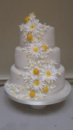 a three tiered cake with daisies on it's side and white icing