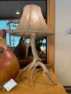 an antler lamp sitting on top of a table next to a vase with a tag