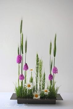 an arrangement of flowers and grass in a vase