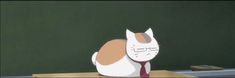 a paper cat sitting on top of a desk in front of a chalkboard with writing on it