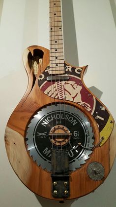 a guitar hanging on the wall with a clock attached to it's back end