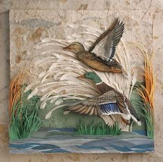 two ducks are flying over the water in front of a stone wall with grass and reeds