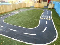 an artificial play area with a stop sign painted on the road and grass surrounding it