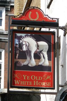 an old white horse sign hanging from the side of a building