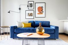 a living room with blue couches and pictures on the wall above it, along with a coffee table