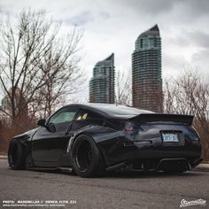 the black sports car is parked on the side of the road in front of tall buildings