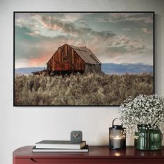 an old barn sits in the middle of a field with flowers on top of it